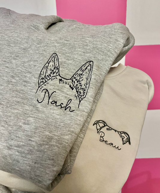 Two gray sweatshirts, one with dog ear embroidery and the name 'Nash' on the front, and the other with a different design, also featuring a dog ear and the name 'Beau'.